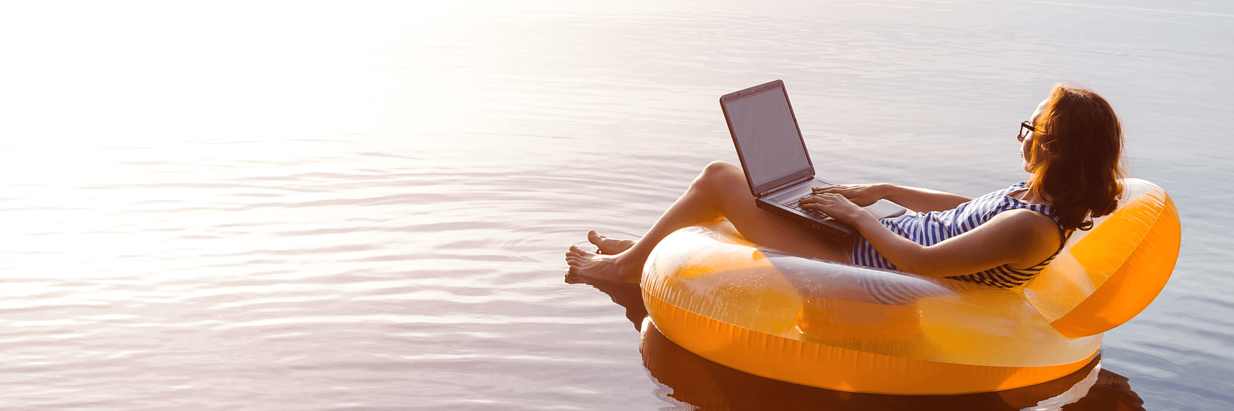 Business woman working on a laptop in an inflatable in the water