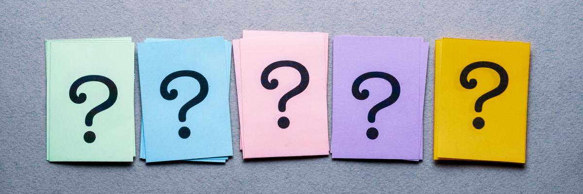 Green, blue, pink, purple, and yellow sticky notes all in a row with single black bold question mark on them