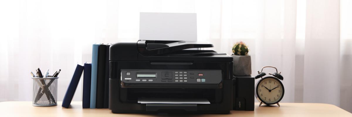 Modern printer and office supplies on wooden table indoors