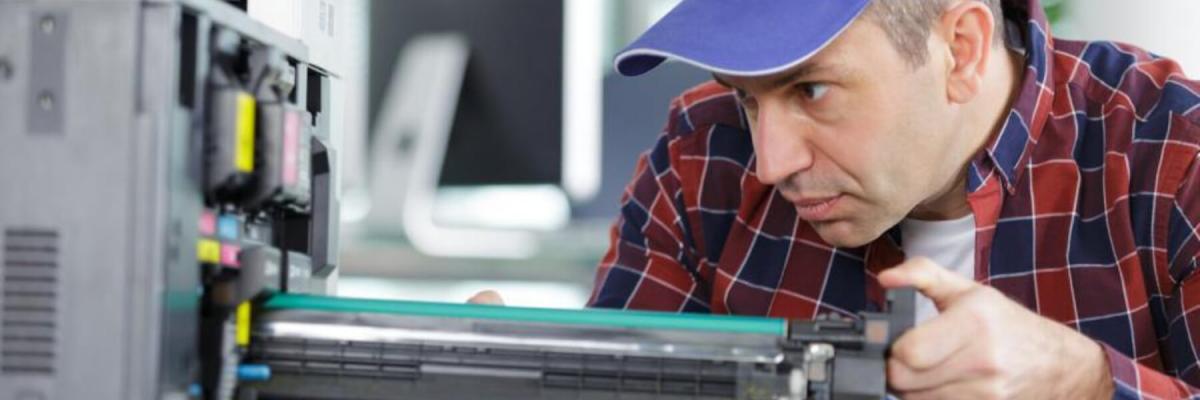 Maintenance man changes printer cartridge in office